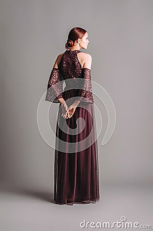 Bridesmaid long sleeve maxi tulle dress with tonal delicate sequin in dark violet. Ginger lady in studio. Fashionable chic loo Stock Photo