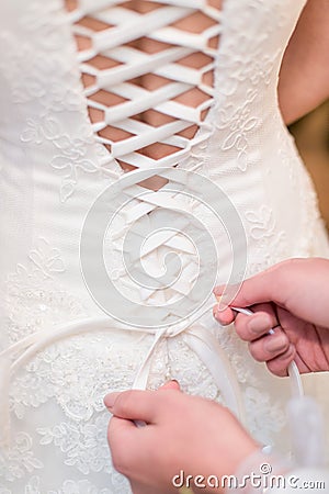 Bridesmaid tying knot on wedding dress Stock Photo