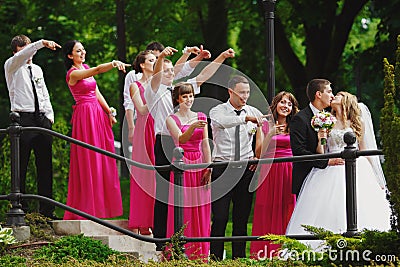 Bridesmaids and groomsmen stare at a kissing wedding couple Stock Photo