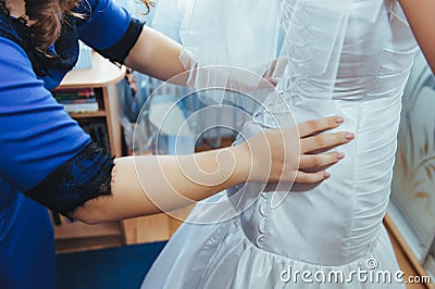 Bridesmaids help dress bride gown. Stock Photo