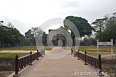 Bridge access to Wat Si Chum complex across moat, with its Giant Buddha visible through a slit in temple wall, Sukhothai, Thailand Stock Photo