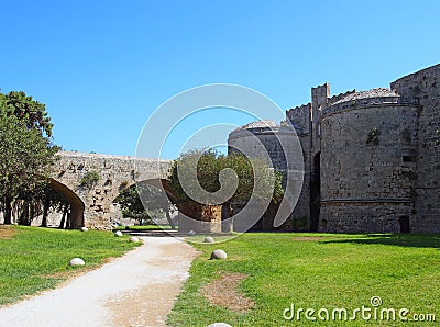 Bridge crossing the amboise gate in the medieval walls of the old city in rhodes town surrounded by grass and trees Stock Photo