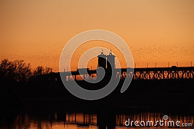 The bridge over the Dnieper against the background of an orange sunset. Kryukovsky road-railway bridge in Kremenchug, Ukraine. Stock Photo