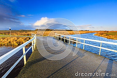 Bridge over river in a rural landscape lit by morning sun Stock Photo