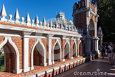 The bridge is of red brick, with white large elements. Tower of red stone with a stone path. Green dense trees. Editorial Stock Photo