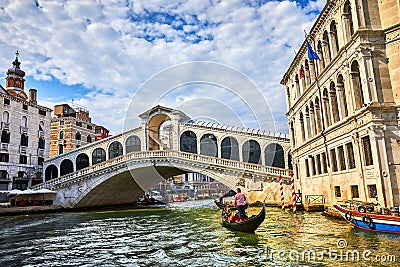 Bridge Rialto on Grand canal famous landmark panoramic view Venice Italy with blue sky white cloud and gondola boat water. Editorial Stock Photo