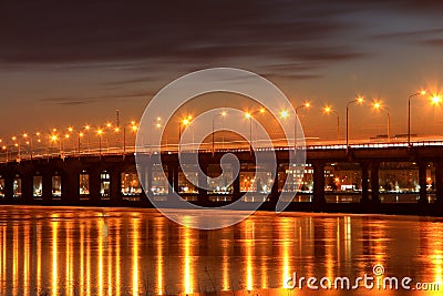 Bridge on the river, the lights reflected on the ice of a frozen river in the evening, Dnieper city. Stock Photo
