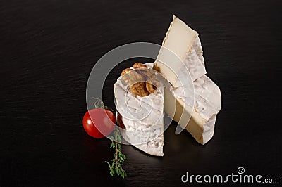 Brie cheese on black background. Brie type of cheese with walnut and tomato. Camembert. Fresh Brie cheese and a slice on stone Stock Photo