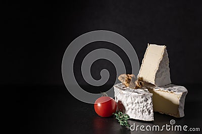 Brie cheese on black background. Brie type of cheese with walnut and tomato. Camembert. Fresh Brie cheese and a slice on stone Stock Photo