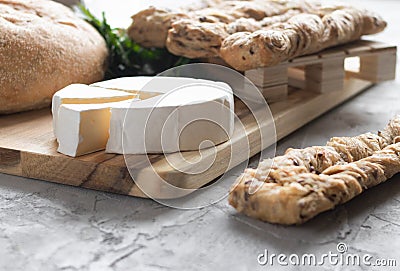 Brie cheese with fersh bread and green parsley on the grey backgrounnd Stock Photo