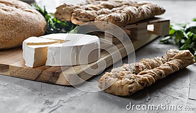 Brie cheese with fersh bread and green parsley on the grey backgrounnd Stock Photo