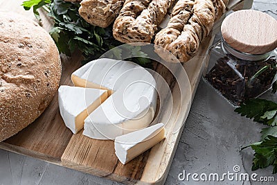 Brie cheese with fersh bread and green parsley on the grey backgrounnd Stock Photo