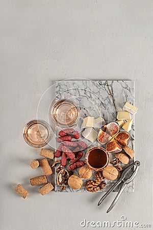 Brie and cheese with paprika, salami, figs, walnuts, honey and rose wine on a marble board. Food for a romantic date on a light Stock Photo