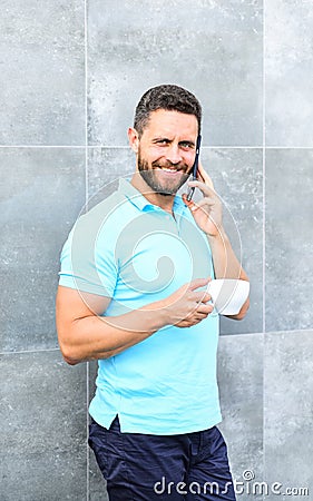 Brief coffee break provides employees with quick ways to relax. Man drink cappuccino speak phone grey wall background Stock Photo