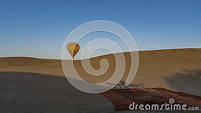 A bright balloon rises above a sand dune. Stock Photo