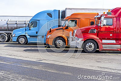 Bright big rigs semi trucks standing in row on truck stop Stock Photo