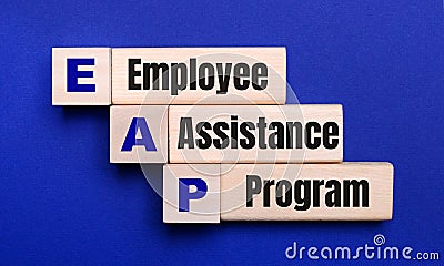 On a bright blue background, light wooden blocks and cubes with the text EAP Employee Assistance Program Stock Photo