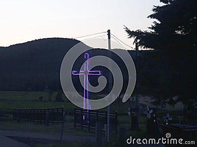 Bright blue cross at dusk in rural countryside Stock Photo