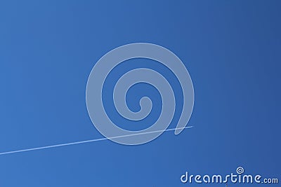Bright blue sky on which the plane flies leaving a trail Stock Photo
