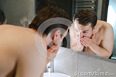 Bright caucasian man spraying water on his face after shaving in the bathroom at home Stock Photo