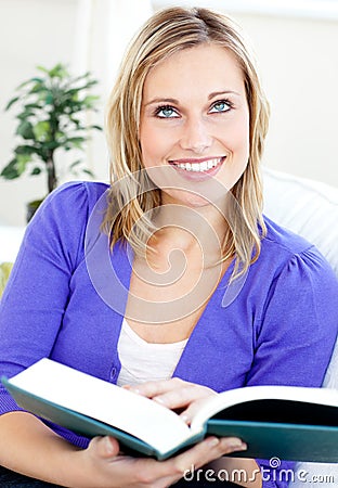 Bright caucasian woman reading a book on the sofa Stock Photo