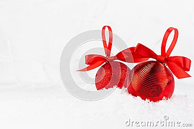 Bright christmas background - two elegant glossy glitter red balls with satin ribbon closeup in decorative fairy white winter. Stock Photo