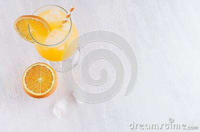 Bright cold tropical orange cocktail of ripe oranges with straw, ice cubes in elegance misted wineglass on white background. Stock Photo