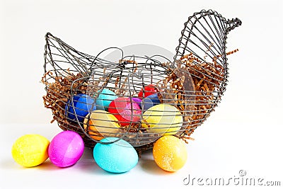 Bright colored Easter eggs in a wire chicken basket. Stock Photo