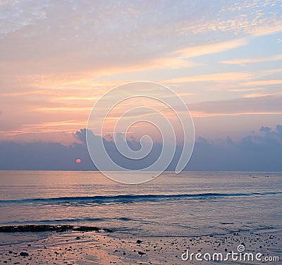 Bright Colors in Morning Sky with Golden Yellow Lines in Clouds and Red Sun Rising at Horizon over Ocean Stock Photo