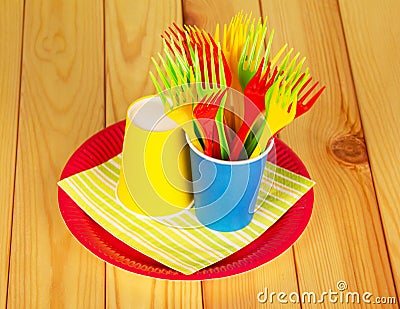 Bright disposable paper cups, plastic forks, plate on alight wood. Stock Photo