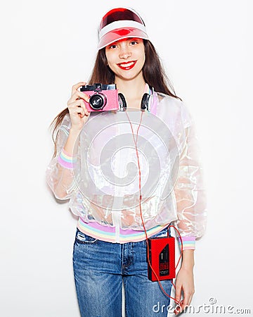 Bright fashionable portrait of a young woman in a trendy outfit with a vintage cassette player, headphones and camera. Stock Photo