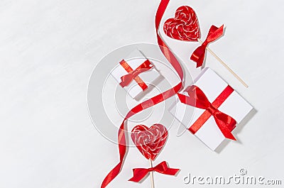 Bright festive wedding background - white gift boxes with red bow, curl ribbon, lollipops hearts on white wood board, copy space Stock Photo