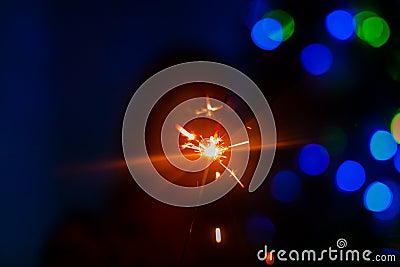Bright flash of sparkler in the hand of a blurred figure of women Stock Photo
