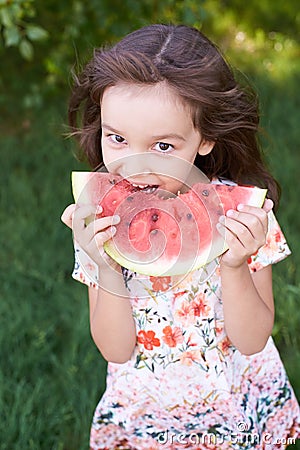 Bright green grass. Little beautiful girl. Juicy, delicious, red Stock Photo