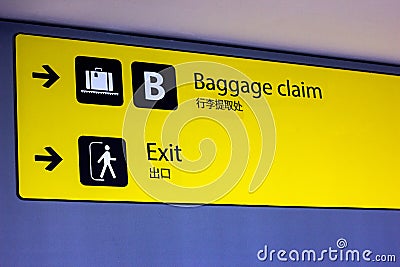 Bright illuminated yellow and black airport signs with arrows and plane icons and the title in Chinese: Baggage claim and Exit. Stock Photo