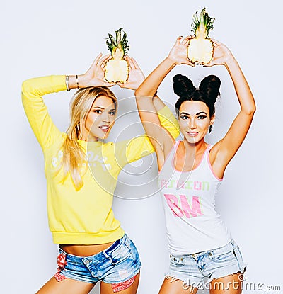 Bright juicy portrait of two cheerful girlfriends, having fun with slice pineapple and smiling. Casual style, bright Stock Photo