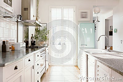 Bright kitchen with modern white furniture, pastel mint fridge and big floor to ceiling window Stock Photo