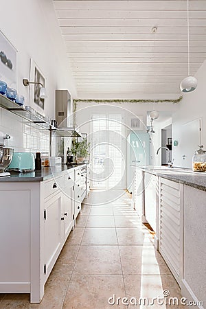 Kitchen interior with modern white furniture, pastel mint fridge and big floor to ceiling window Stock Photo