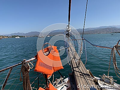 A bright life jacket on board the yacht. Railings of a sea ship against the background of the sea and mountains. A vest for Stock Photo