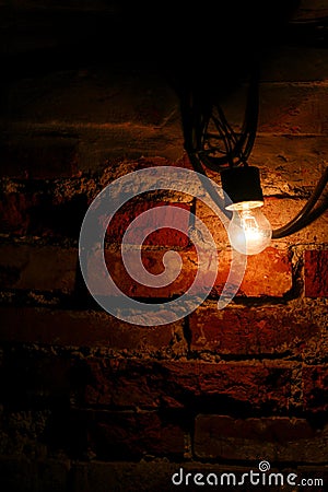 Bright light bulb next to an old brick wall Stock Photo