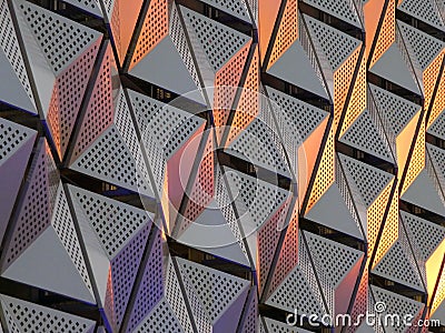 Modern geometric triangular shiny silver steel cladding with highlights in gold and copper tones and perforated design Stock Photo