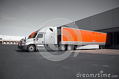 Bright modern orange and gray semi trucks unloading in warehouse Stock Photo