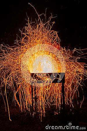 Bright orange flying sparks from barbecue in windy night Stock Photo