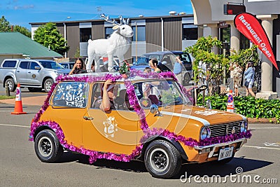 An orange Mini, decorated with tinsel and a reindeer, taking part in a Christmas parade Editorial Stock Photo