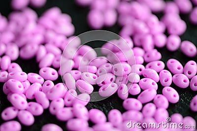 Bright pink twin beads scattered on a dark surface Stock Photo