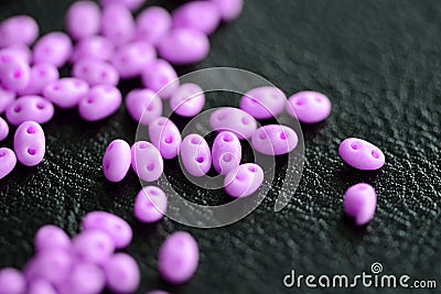 Bright pink twin beads scattered on a dark surface Stock Photo
