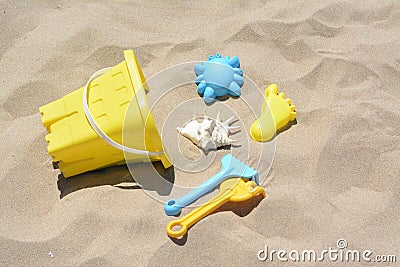 Bright plastic bucket and rakes on sand. Beach toys Stock Photo