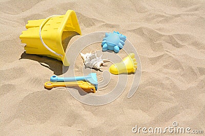 Bright plastic bucket and rakes on sand. Beach toys. Space for text Stock Photo
