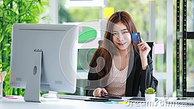 Bright pretty businesswoman sitting in her modern office showing credit card, looking straight at a camera. Online shopping, Stock Photo