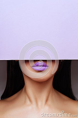 Bright purple lips looks into the hole of the colored paper. Stock Photo